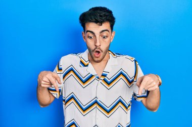 Gündelik giysiler giymiş genç İspanyol bir adam parmaklarını göstererek reklamını yapıyor, şaşırmış bir yüz ve ağzını açıyor. 