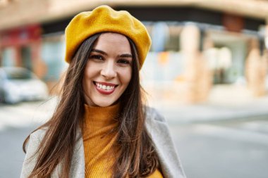 Genç İspanyol kız gülümseyerek şehirde mutlu mesut dikiliyor..