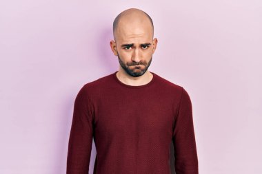 Gündelik kıyafetler giyen, kuşkucu ve gergin genç kel bir adam sorun yüzünden surat asıyor. negatif kişi. 