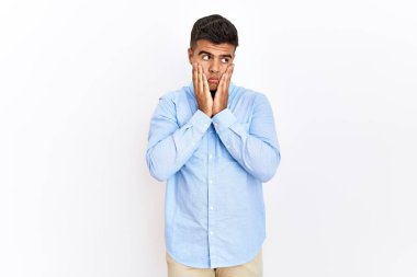 İzole edilmiş arka plan üzerinde duran İspanyol gömleği giyen genç adam yorgun eller yüzünü, depresyonu ve üzüntüyü örten, sorun yüzünden üzgün ve tedirgin 