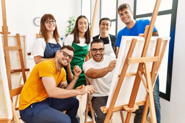 Mutlu gülümseyen ve ortak arayan bir grup insan sanat stüdyosunda..