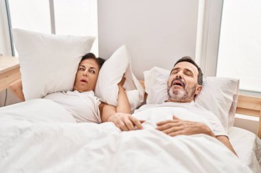 Orta yaşlı erkek ve kadın çift yatak odasında horladıkları için mutsuz.