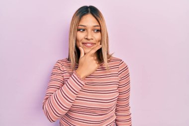 Güzel İspanyol kadın sıradan çizgili süveter giyiyor, elleri çenesinde soru soruyor, düşünceli bir yüz ifadesi var. Düşünceli bir yüzle gülümsüyor. şüphe kavramı. 