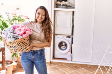 Çamaşır yıkayan genç İspanyol kız elinde sepetle evde giysiler tutuyor.