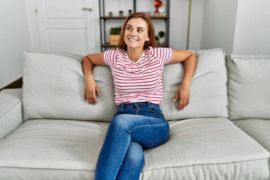 Evdeki koltukta kendinden emin gülümseyen genç bir kadın.