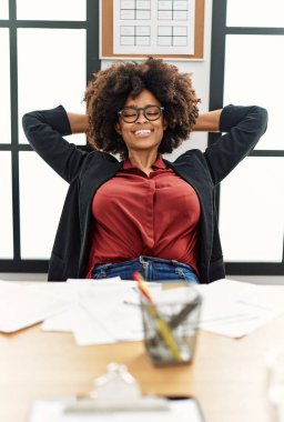 Genç Afro-Amerikalı kadın, elleri ofiste çalışırken rahat.