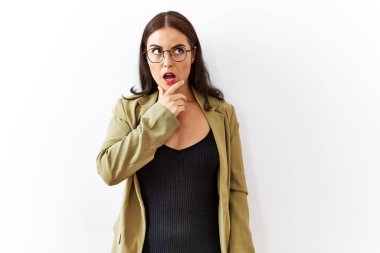 Soyutlanmış arka planda duran genç esmer kadın elleri çenesinde olan inançsızlığa, şaşkınlığa ve hayrete düşmüş bir ifadeye bakıyor. 