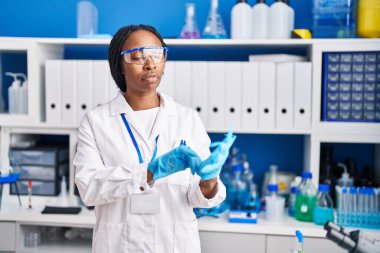 Bilim adamı üniforması ve eldiven laboratuarı giyen Afrikalı Amerikalı kadın.