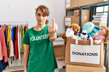 Beautiful caucasian woman wearing volunteer t shirt at donations stand showing middle finger, impolite and rude fuck off expression 
