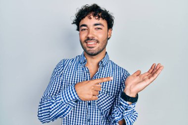 Gündelik kıyafetler giyen genç İspanyol adam kameraya hayret ediyor ve gülümsüyor.. 