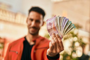 Genç İspanyol gülümseyen adam Hindistan Rupisi 'ni şehirde tutarken mutlu..