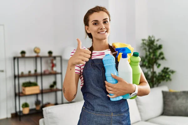 Önlük Takan Esmer Kadın Temizlik Ürünlerini Tutarken Mutlu Pozitif Gülümsüyor — Stok fotoğraf