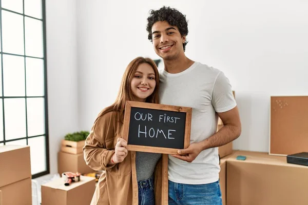 Jovem Casal Sorrindo Feliz Segurando Quadro Negro Com Nossa Primeira — Fotografia de Stock