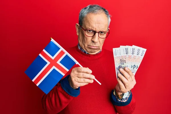 白发苍苍 头戴冰原旗 头戴冰岛式冰岛克朗钞票的英俊老人 满脸怀疑和紧张 因为问题皱着眉头 消极的人 — 图库照片