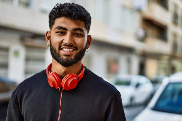 Young arab man smiling confident wearing headphones at street