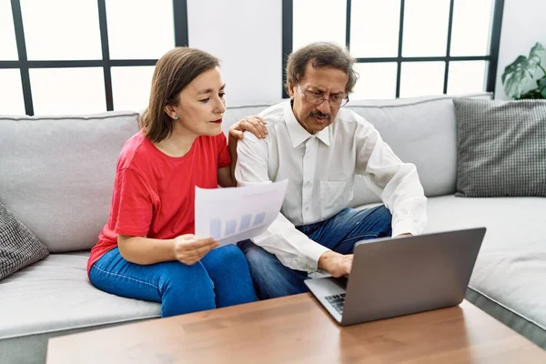Middle age man and woman couple smiling confident using laptop working at home