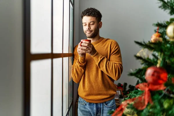 Νεαρός Άραβας Πίνει Καφέ Δίπλα Στο Χριστουγεννιάτικο Δέντρο Στο Σπίτι — Φωτογραφία Αρχείου
