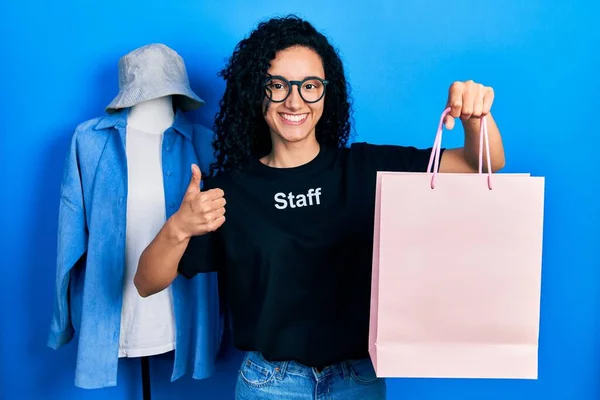 Young Hispanic Woman Curly Hair Wearing Staff Shirt Holding Shopping —  Fotos de Stock