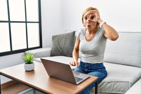 Middle Age Blonde Woman Using Laptop Home Doing Gesture Shocked — Stockfoto