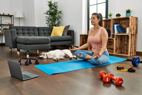 Young woman having online yoga class at home