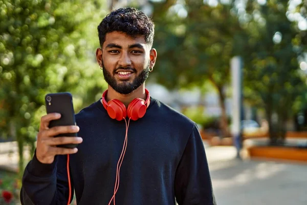 Young arab man smiling confident using smartphone at park