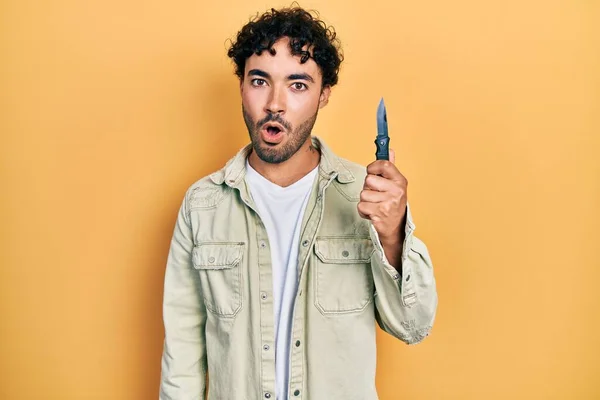 Young Hispanic Man Holding Pocket Knife Scared Amazed Open Mouth — Foto de Stock