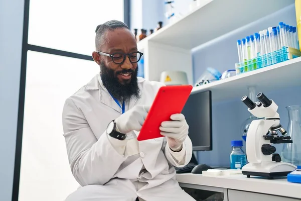 研究室でタッチパッドを使って科学者の制服を着た若いアフリカ系アメリカ人男性 — ストック写真