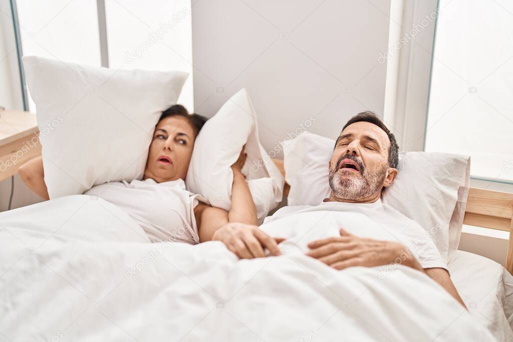 Middle age man and woman couple unhappy for snoring at bedroom