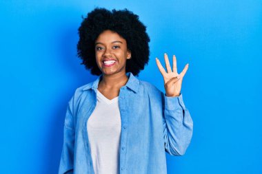 Genç Afro-Amerikalı kadın, günlük kıyafetler giyip dört numaralı parmaklarıyla işaret ederken kendinden emin ve mutlu bir şekilde gülümsüyor.. 
