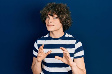 Yakışıklı, çizgili tişört giyen, tiksindirici, tiksindirici, tiksindirici, tiksindirici bir ifade takınan genç bir adam. Eller havada. 