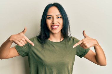 Gündelik tişört giyen genç İspanyol kız. Kendine güvenen, yüzünde gülümseme olan, kendini gururlu ve mutlu gösteren kız.. 