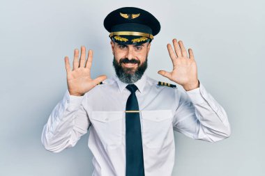 İspanyol asıllı genç adam uçak pilotu üniforması giyiyor. Kendini beğenmiş ve mutlu bir şekilde gülümserken on numarayı gösterip işaret ediyor.. 