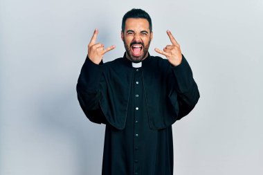 Sakallı, Katolik rahip cübbesi giymiş yakışıklı, çılgın bir ifadeyle bağıran, elleri havada rock sembolü yapan yakışıklı bir İspanyol. Müzik yıldızı. ağır müzik konsepti. 