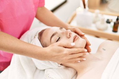 Beyaz kadın güzellik merkezinde yüz masajı yaptırıyor..