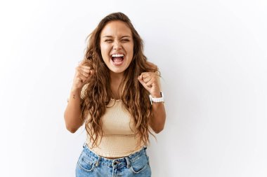 Güzel İspanyol kadın tecrit edilmiş bir şekilde ayakta dururken arka planda şaşkınlık ve şaşkınlık içinde kollarını kaldırarak ve gözlerini açarak başarıyı kutluyor. Kazanan konsept. 