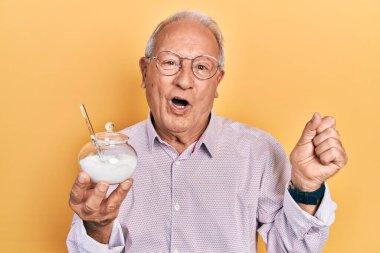 Yaşlı adam elinde şeker dolu kaseyle gururla bağırıyor zaferi ve başarıyı kutluyor. Kollarını kaldırarak heyecanlanıyor. 