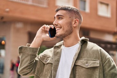 Genç İspanyol adam gülümsüyor. Kendine güveniyor. Sokakta akıllı telefondan konuşuyor.
