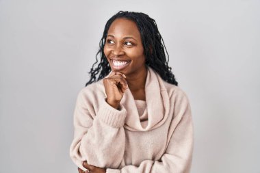 Beyaz arka planda duran Afrikalı kadın, elleri çenesinde soru sormayı, düşünceli ifadeyi düşünüyor. Gülümseyen ve düşünceli bir yüz. şüphe kavramı. 