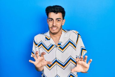 Gündelik kıyafetler giyen genç İspanyol adam tiksindirici bir ifade takınıyor ve tiksindirici bir yüz ifadesi takınıyor.. 