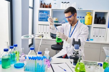 Laboratuvarda pipeti kullanarak sıvıyı ölçen genç İspanyol bilim adamı.