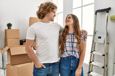 Beyaz bir çift gülümsüyor. Yeni evlerinde birbirlerine sarılıyorlar.