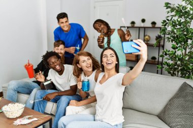 Bir grup genç arkadaş evdeki akıllı telefondan komik aksesuarlar kullanarak selfie çekiyorlar..