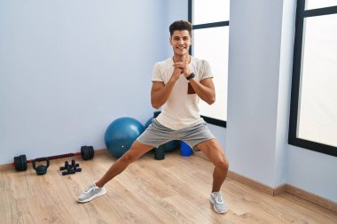 Genç İspanyol adam gülümsüyor spor merkezinde esniyor.