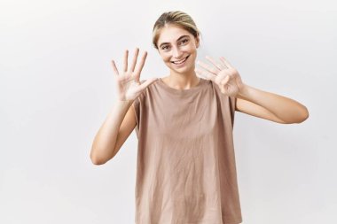 İzole edilmiş arka planda duran genç sarışın kadın dokuz numarayı gösteriyor ve gülümserken kendinden emin ve mutlu.. 