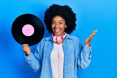 Genç Afrikalı Amerikalı kadın kulaklık takıyor. Plastik disk taşıyor. Başarı kutlamalarını mutlu bir gülümsemeyle kutluyor. 