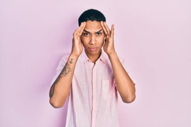 Genç Afro-Amerikalı adam gündelik kıyafetler giyiyor. Baş ağrısı çekiyor, çaresiz ve stresli. Çünkü acı ve migren ağrısı var. Eller başının üstünde.. 