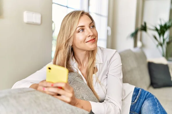 Mujer Rubia Joven Usando Teléfono Inteligente Sentado Sofá Casa — Foto de Stock