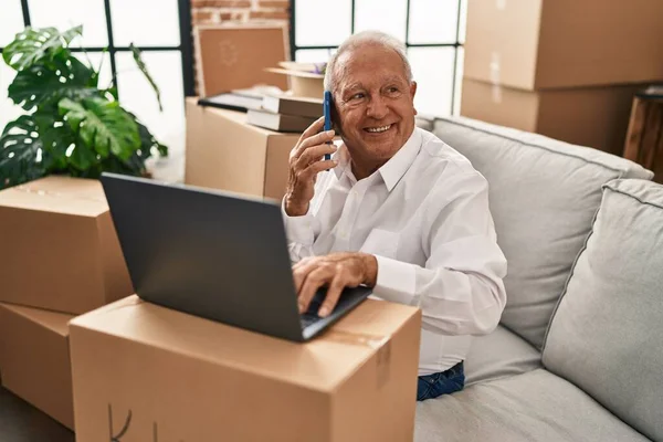 Hombre Mayor Usando Ordenador Portátil Hablando Teléfono Inteligente Nuevo Hogar — Foto de Stock