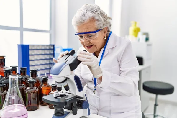 Starsza Siwowłosa Kobieta Mundurze Naukowca Używająca Mikroskopu Laboratorium — Zdjęcie stockowe