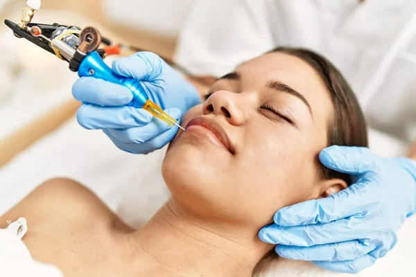 Young latin woman relaxed having microblading lips treatment at beauty center